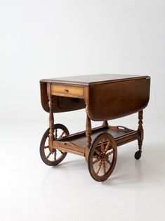 "This is a mid 20th century serving cart.  The Colonial style tea or bar cart features a drop leaf table top with a removable shelf tray for serving, and a single drawer. CONDITION In good condition with wear consistent with age and use.  Some finish flaws to the table top.  MEASUREMENTS Height:  29\"  ..  73.7 cm Length: 32\"  ..  81.3 cm Width:  20.75\"  ...  52.7 cm Width Open:  41\"  ..  104.1 cm Shelf Height:  10\"  .. 25.4 cm SHIPPING Home delivery via a blanket wrap service.  Delivery estimate in 4-6 weeks.  Faster shipping available. Please contact us for expedited options and pricing.  International and non-contiguous US customers, please contact us for shipping options and pricing based on your location. 82311" Mid Century Colonial, Serving Cart, Woven Baskets Storage, Top Measurements, Drop Leaf Table, Bar Items, Vintage Studio, Bar Carts, Leaf Table