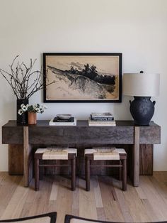 a table with two stools and a painting on the wall above it in a living room