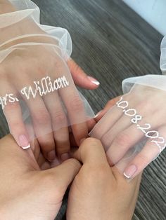 two hands holding each other with wedding rings on their fingers and name written on them