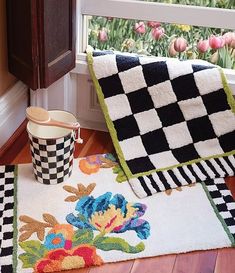 a black and white rug sitting on top of a wooden floor next to a window