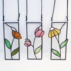 three stained glass vases with flowers hanging from the sides, each holding a single flower