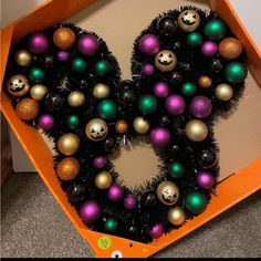 an orange box filled with lots of different colored christmas balls and decorations in the shape of a heart