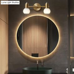 a bathroom with a round mirror and lights on the wall above it, along with a black sink