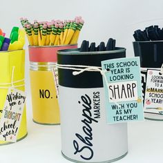 three tins with school supplies in them on a white surface, one is empty and the other has stickers attached to it