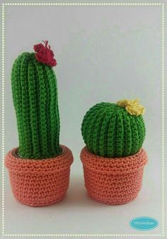 two crocheted cactus plants sitting in small pots with flowers on them, one is green and the other is pink