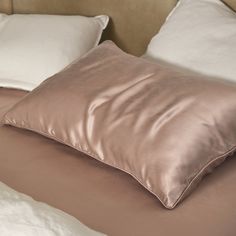 a bed with two pillows on top of it and one pillow is folded up to the side