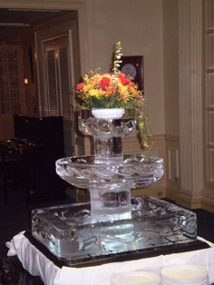 there is a glass vase with flowers in it on top of a cake platter