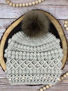 a white crocheted hat with a brown pom - pom on top