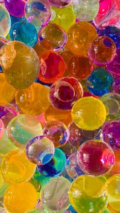 many different colored glass beads are in the shape of balls and circles, as if they were floating or floating on top of each other