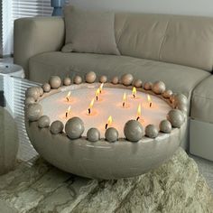 a cake with lit candles sitting on top of a table next to a white couch