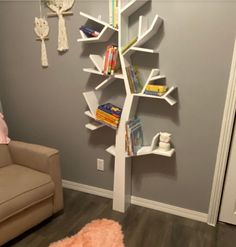 a white tree shaped book shelf in a child's room