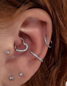 a woman wearing three different types of ear piercings