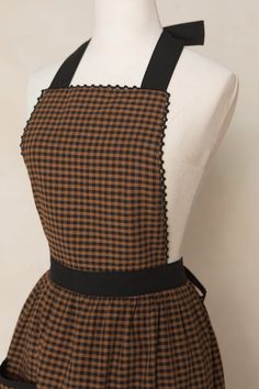 a mannequin wearing a brown and black checkered dress with an apron on it