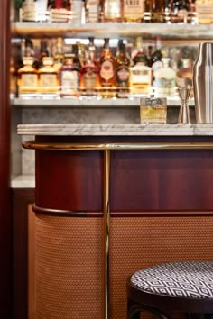 a bar with liquor bottles behind it and a stool next to it in front of the bar