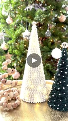 two small christmas trees sitting on top of a table next to a christmas tree and ornaments