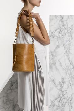 Roxanne bucket bag is handmade of high quality calf leather that comes in camel (waxed tan), black, nude (nubuck ) and blue (nubuck). It features our signature chain strap in two sizes, short to use as a tote or long to wear it cross-body. Roomy enough yet elegant and classy, will hold your daily essential in style. Greek Chic Handmades Bags are handcrafted in Athens and designed to accompany you everywhere. From the city to beach escapades and resort evenings. Unique Leather Bag, Boho Leather Bags, Handmade Leather Tote, Blue Leather Bag, Handmade Leather Backpack, Tan Leather Bag, Tan Shoulder Bag, Leather Sandals Handmade, Handmade Sandals