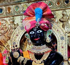 an idol is displayed in front of gold and red decorations, including a blue headdress