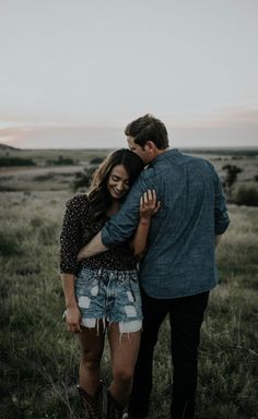 a man and woman hugging in the middle of a field