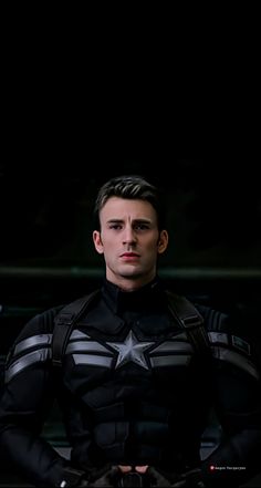 a man dressed as captain america sitting in the dark with his hands on his hips