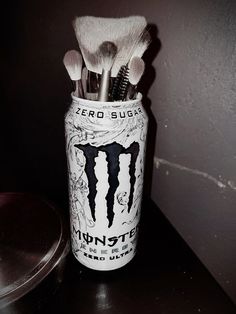 a jar filled with brushes sitting on top of a table next to a container full of toothbrushes