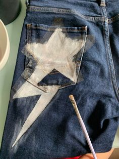 a pair of blue jeans with a white star painted on the side and a pencil sticking out of it