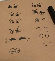 an image of different faces drawn on a piece of paper with a pen next to it