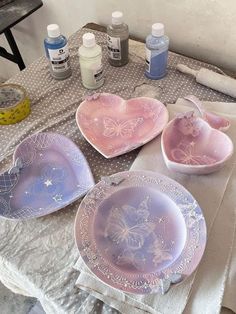 three pink plates sitting on top of a table next to bottles of paint and glue