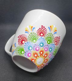 a white coffee cup with multicolored flowers painted on the outside and inside, sitting on a gray surface