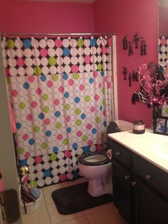 a bathroom decorated in pink, green and white with polka dots on the shower curtain