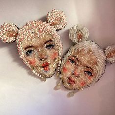 two pieces of beaded art that look like people's heads with bows on them