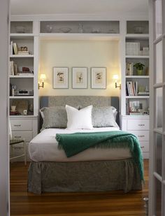 a bed sitting inside of a bedroom next to a white book shelf filled with books