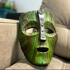 a green mask sitting on top of a couch