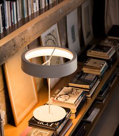 a lamp sitting on top of a wooden table next to a book shelf filled with books