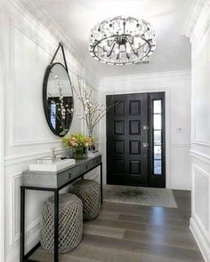 a hallway with a table, mirror and vases on the side tables in front of it