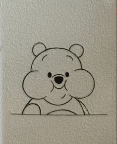 a drawing of a teddy bear on a white wall with the outline of it's face