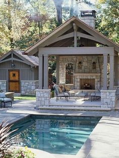 an outdoor living area next to a swimming pool with lounge chairs and fire place in the background