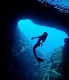 a person swimming in the water near a cave