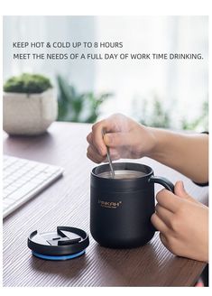 a person is holding a spoon in a coffee mug while sitting at a computer desk