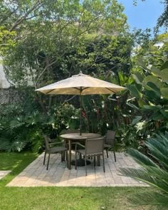 an outdoor table and chairs with umbrellas in the middle of a small garden area