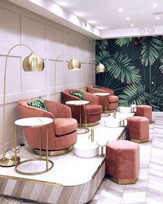 a room filled with lots of pink chairs and gold tables in front of a wall