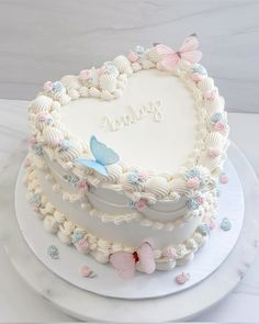 a heart shaped cake on a plate with the word love spelled in frosting and butterflies around it