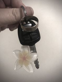 a hand holding a key with a flower on it and a ring attached to it