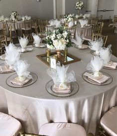 the table is set with white flowers and gold place settings for an elegant wedding reception