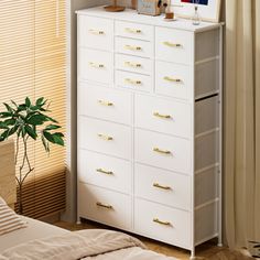 there is a white dresser with gold handles in the room next to a bed and window