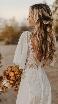 a woman with long hair wearing a white dress and holding a bouquet in her hand