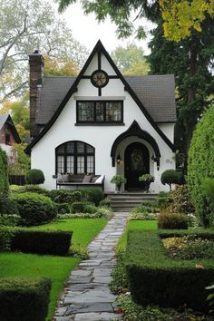 White Tudor-style home with dark trim and lush garden. The charming fusion of history and contemporary flair in modern Tudor houses can transform your living space from “just nice” to “royalty-approved.” Tudor Cottage Garden, Tudor Bedroom, 1900s House, Fantasy Houses, Cozy Houses