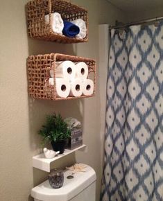 the bathroom has two baskets on the wall above the toilet and one is filled with towels