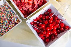 two bowls filled with cherries and sprinkles on top of a table