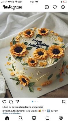 a cake decorated with sunflowers on top of a white sheet covered in icing