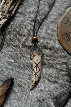 a necklace with an arrow on it sitting on a fur surface next to other items